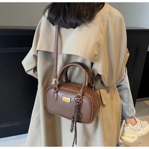 Detail der braunen Bowling-Tasche mit Doppelgriffen und geflochtenem Seilanhänger