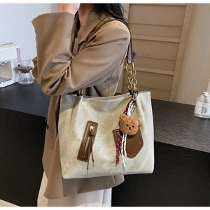 Detail of shoulder tote bag with gold chain strap and cute teddy bear charm pendant