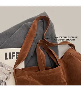 Close-up of brown suede tote bag with wide shoulder strap against wool blazer background