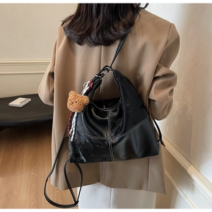 Détail du sac Hobo en cuir PU noir avec coutures blanches et breloque ourson
