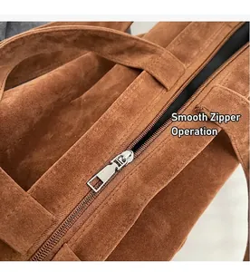 Detail of smooth metal zipper and precision stitching on brown suede leather handbag