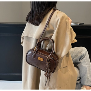 Detailansicht einer braunen Boston-Tasche mit goldenem Fashion Accessory Emblem