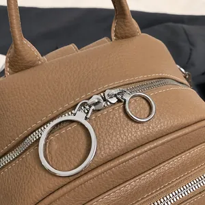 Detail von silbernen Reißverschlüssen und genarbtem Leder am braunen Rucksack