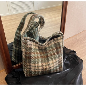 Detailopname van de groen en bruin geruite tote bag op zwarte satijnen achtergrond