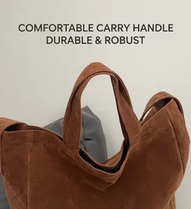 Detail of a brown suede tote bag with durable wide handles and secure zipper closure