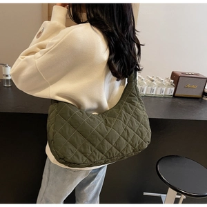 Detailed side view of green quilted hobo shoulder bag worn by model in a cozy setting