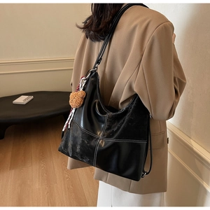 Détail d'un grand sac cabas noir en similicuir avec surpiqûres et pendentif ours