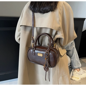 Makroaufnahme der dunkelbraunen Lederstruktur und Goldplakette auf der Boston Bag Tasche