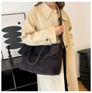 Detail of black corduroy tote bag with woven rope handle and adjustable crossbody strap