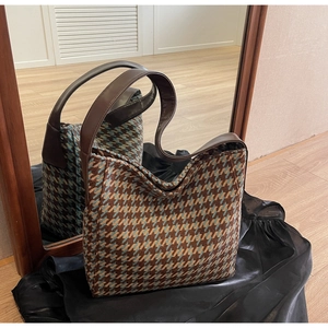 Detail van blauw-bruine houndstooth-tas met lederen riem op zijden stof