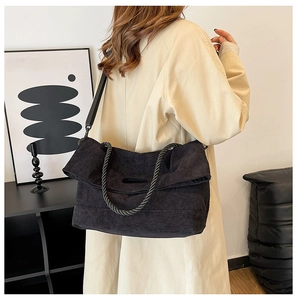 Detail of black corduroy tote bag with woven rope handles and adjustable shoulder strap