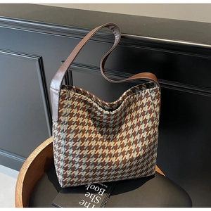 Detail van vintage houndstooth tote tas met bruine leren riem op getextureerd meubilair