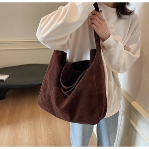 Close-up of a large dark brown suede tote bag carried by a model for daily commute