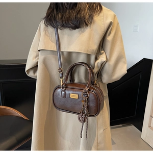 Dunkelbraune zylindrische Umhängetasche kombiniert mit einem beigen Trenchcoat für Damen
