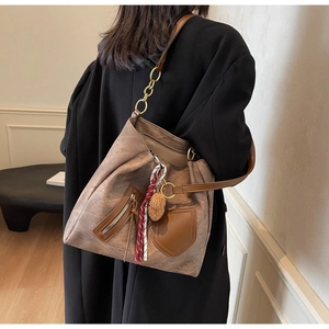 Detail of deep brown tote bag with zipper pocket and leather-chain shoulder strap
