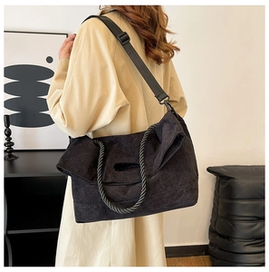 Detail of black corduroy tote bag showing textured fabric and braided rope handle