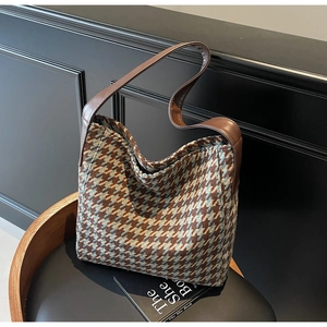 Detail van retro houndstooth tweed schoudertas met donkerbruine leren riem op een stoel