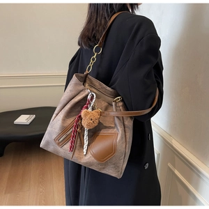 Detail of vintage brown tote bag with metal zipper pocket and luxury plush bear pendant