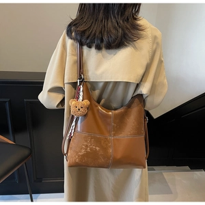 Détails d'un sac cabas vintage marron avec surpiqûres blanches et charme ours en peluche