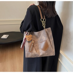 Detailed view of large brown vintage leather tote bag with metal chain strap and bear charm