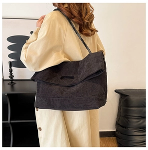 Detail of black corduroy tote bag featuring a unique thick woven rope shoulder strap