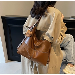 Détail du sac cabas marron avec coutures blanches contrastées et charm ourson mignon