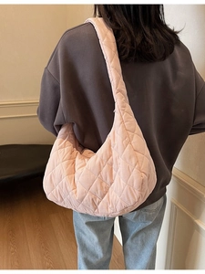 Pink quilted rhombus shoulder bag with minimalist crescent shape on female model