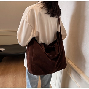 Detail view of a large brown vintage suede tote bag worn on shoulder by a model