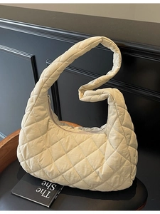 Quilted cream hobo bag with padded diamond lattice pattern shown on a vintage chair