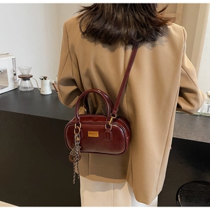 Detail der burgunderroten Boston-Tasche aus Leder mit Gold-Beschlägen und edlem Seidenschal