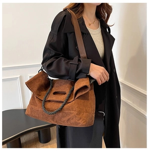 Close-up of brown corduroy tote bag with black woven handles and broad shoulder strap