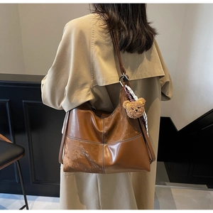 Sac hobo en cuir marron avec surpiqûres blanches contrastées et breloque ours