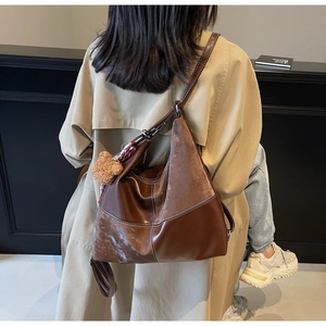 Détail d'un sac cabas patchwork marron foncé avec surpiqûres et breloque ours en peluche