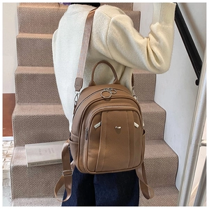 Detail eines braunen Lederrucksacks mit silbernen Ringreißverschlüssen auf Treppen