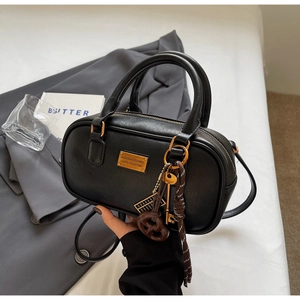 Detailansicht der schwarzen Retro-Bowlingtasche mit goldenen Anhängern und Ledertextur