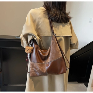 Détails du sac fourre-tout marron vintage avec textures de cuir et breloque ours