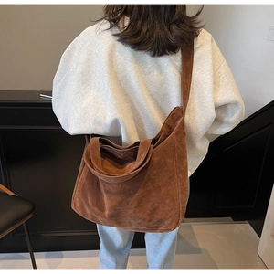 Brown frosted suede tote bag being worn as a crossbody by a model in casual setting