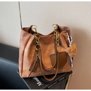 Detailed shot of tan suede tote bag with chain strap and cute plush bear charm decoration