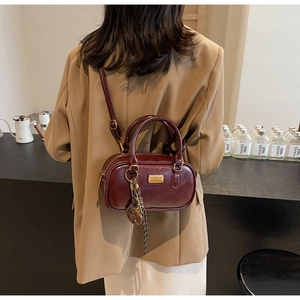 Detail der dunkelroten Boston Bag mit Glanzeffekt und dekorativem Karoband-Anhänger