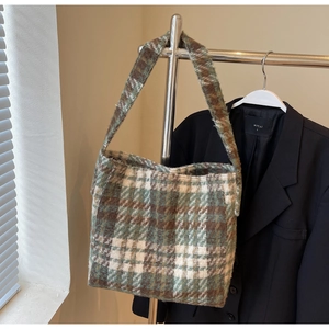 Detailopname van de Schotse ruit tote bag van wol met textuur aan een kledingrek