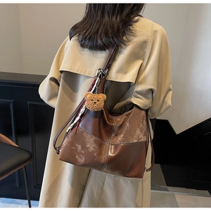 Sac cabas marron porté au dos avec breloque ours et foulard à carreaux détaillé