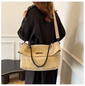 Detail of light yellow corduroy tote bag with black braided handles and beige strap