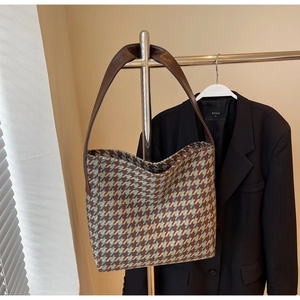Detail van vintage houndstooth shopper met bruine lederen riemen aan een hanger
