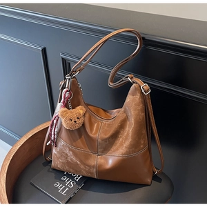 Détail du sac hobo marron avec texture en daim et accessoire mignon en peluche d'ours
