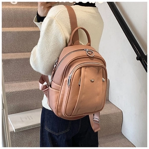 Detail eines rosa Kunstleder-Mini-Rucksacks mit silbernen Reißverschlüssen und Trägern