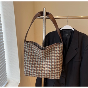 Detail van geweven tote bag met pied-de-poule patroon en donkerbruine handvaten
