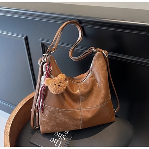Détails du sac hobo rétro marron avec surpiqûres contrastées et breloque ours en peluche