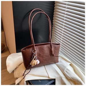 Close-up of a brown vintage tote bag with a baseball charm in natural window light