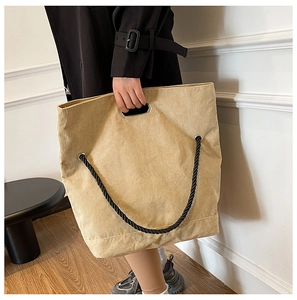Close-up detail of beige corduroy tote bag featuring black rope straps and woven texture