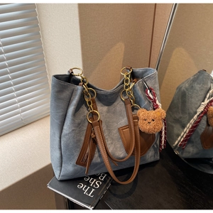 Detail of a large contrast tote bag with leather straps and plush bear ornament